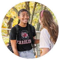 two students facing each other talking and smiling