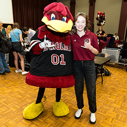 mascot cocky standing with student at an expo