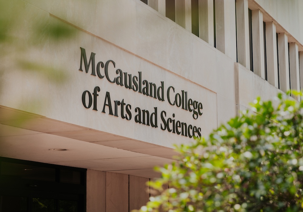 beige building with black 'McCausland College of Arts and Sciences' on the facade
